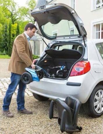 Man packing away a disability scooter A man storing a mobility scooter in the boot of a car